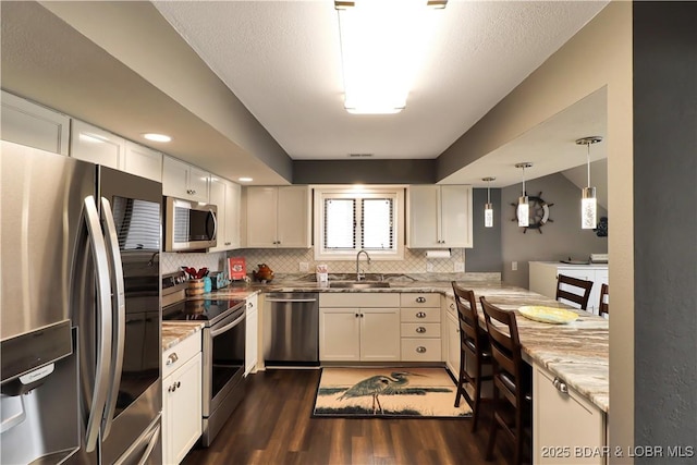 kitchen with stainless steel appliances, hanging light fixtures, dark wood-type flooring, and white cabinets