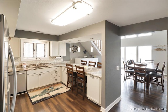 kitchen featuring a healthy amount of sunlight, appliances with stainless steel finishes, sink, and white cabinets