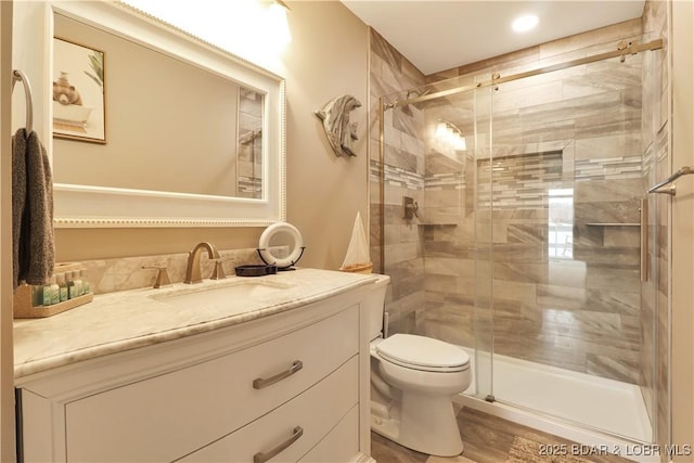 bathroom featuring vanity, toilet, and a shower with door