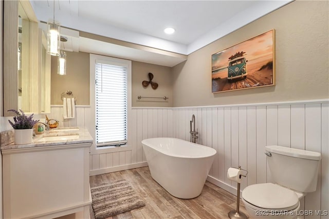 bathroom featuring a washtub, vanity, wood-type flooring, and toilet