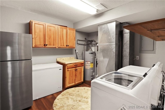 clothes washing area with dark hardwood / wood-style floors, washing machine and dryer, water heater, and a textured ceiling