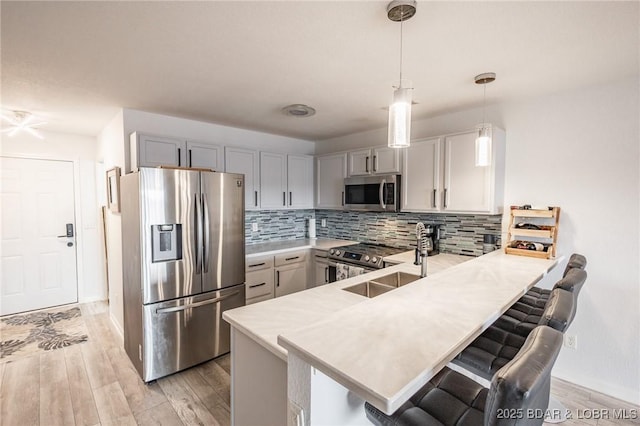 kitchen featuring sink, a breakfast bar area, decorative light fixtures, kitchen peninsula, and stainless steel appliances