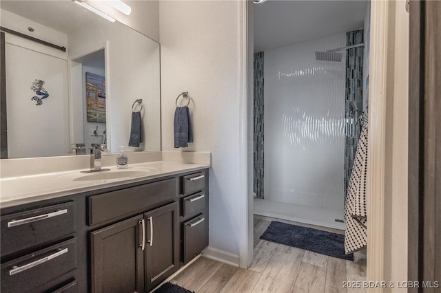 bathroom featuring hardwood / wood-style flooring, vanity, and a shower