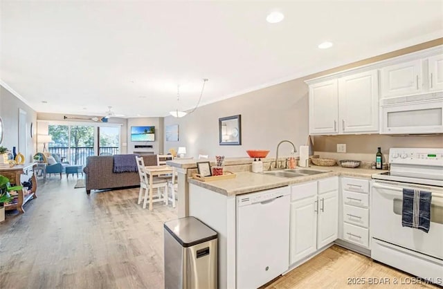 kitchen with sink, crown molding, white appliances, white cabinets, and kitchen peninsula