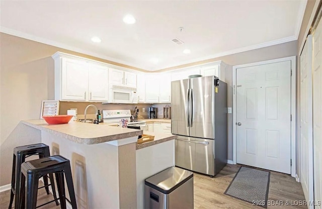 kitchen featuring white cabinetry, light wood-type flooring, ornamental molding, kitchen peninsula, and white appliances