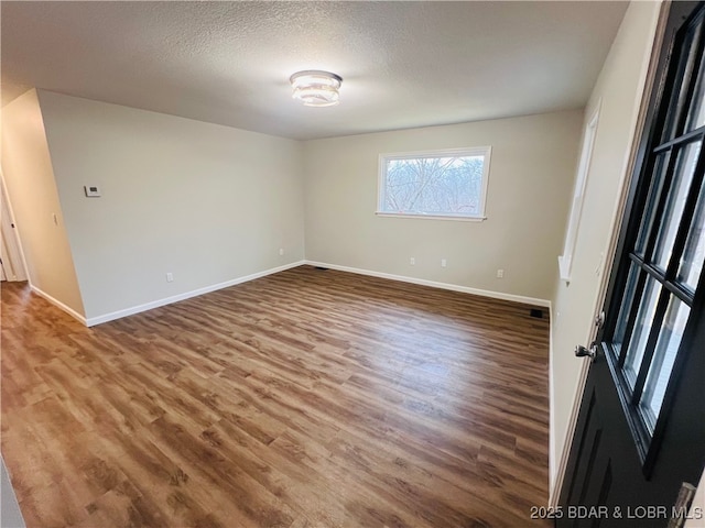 empty room with hardwood / wood-style flooring and a textured ceiling