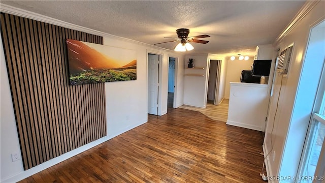 spare room with crown molding, wood finished floors, a textured ceiling, a ceiling fan, and baseboards