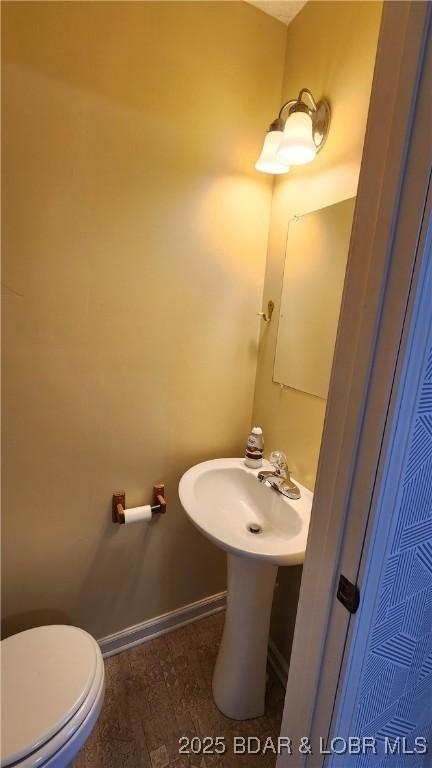 half bathroom featuring toilet and baseboards