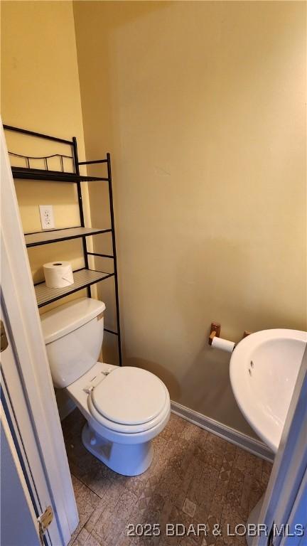 bathroom with toilet and baseboards
