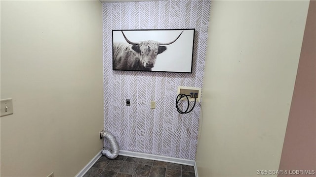 washroom with an accent wall, wallpapered walls, baseboards, and hookup for a washing machine