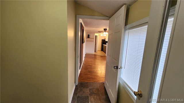 corridor featuring vaulted ceiling and a textured ceiling