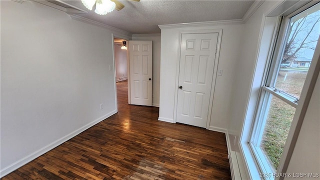 empty room with ceiling fan, dark wood-style flooring, healthy amount of natural light, ornamental molding, and a textured ceiling