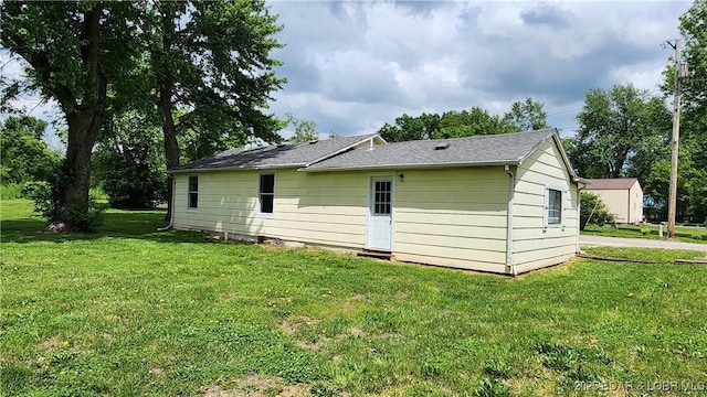 rear view of property with a yard and a shingled roof