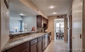 kitchen featuring light stone counters, light tile patterned floors, and dark brown cabinets