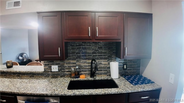 kitchen with light stone countertops, sink, dishwasher, and backsplash