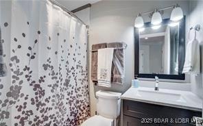 bathroom with walk in shower, vanity, and toilet