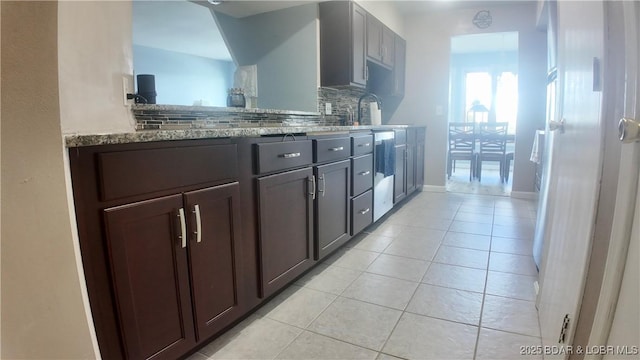 kitchen featuring light tile patterned floors, sink, dark brown cabinets, light stone counters, and tasteful backsplash