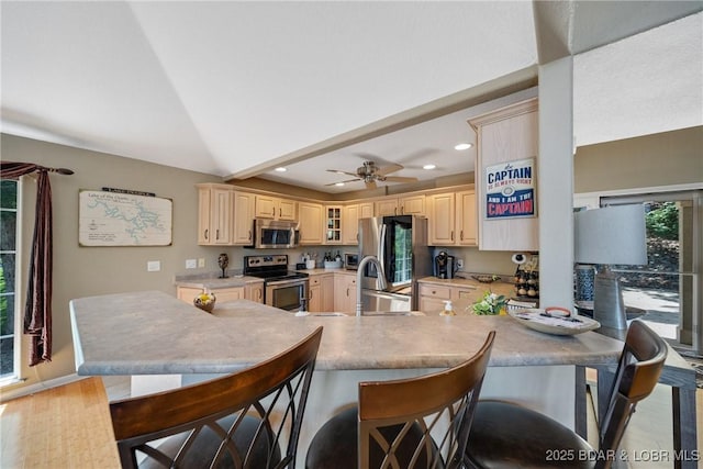 kitchen featuring vaulted ceiling, appliances with stainless steel finishes, a kitchen breakfast bar, kitchen peninsula, and ceiling fan