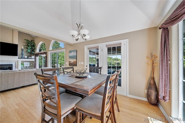 dining area featuring a chandelier, light hardwood / wood-style floors, and vaulted ceiling