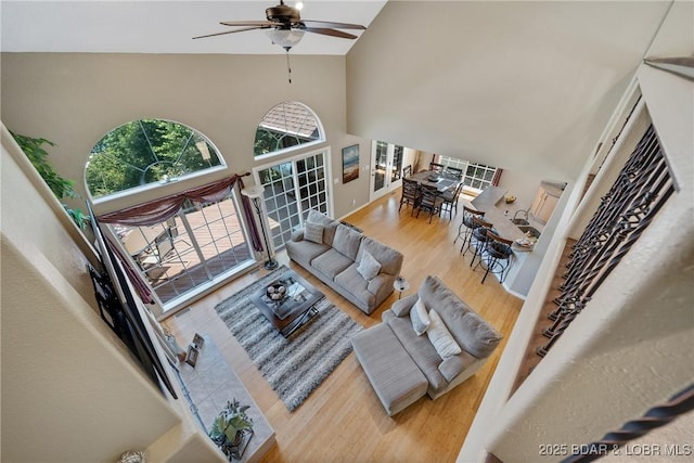 living room with hardwood / wood-style flooring, ceiling fan, and high vaulted ceiling