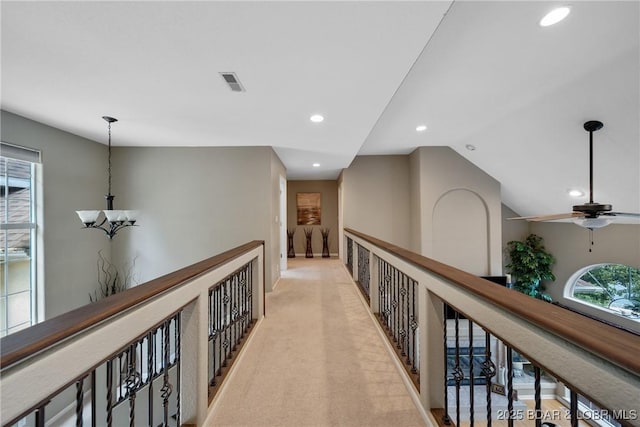 hallway with light carpet, vaulted ceiling, and a chandelier