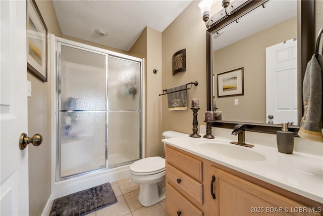 bathroom featuring tile patterned flooring, vanity, a shower with door, and toilet