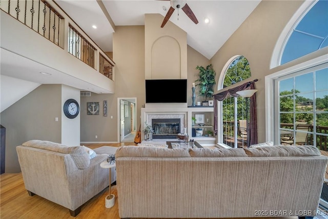 living room featuring light hardwood / wood-style flooring, high vaulted ceiling, and ceiling fan