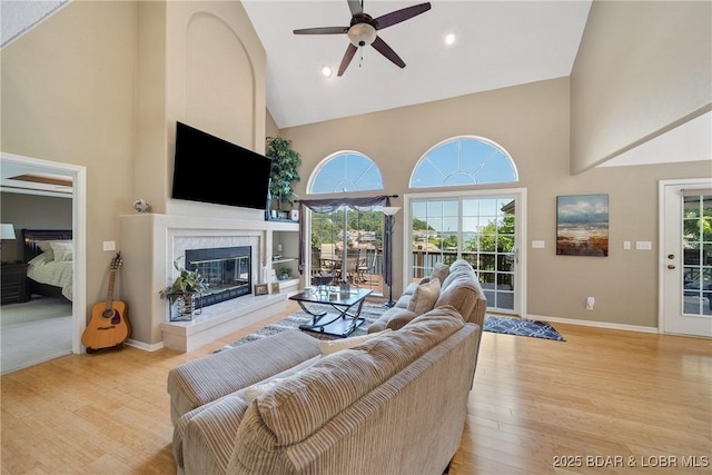 living room with ceiling fan, high vaulted ceiling, plenty of natural light, and light hardwood / wood-style floors