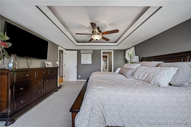 bedroom featuring a tray ceiling, light colored carpet, and ceiling fan