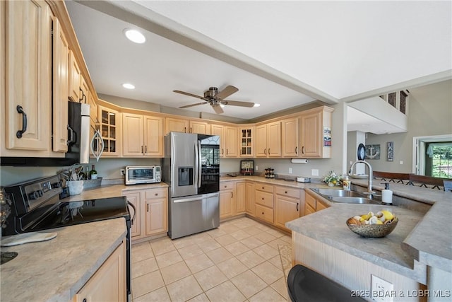 kitchen featuring appliances with stainless steel finishes, light brown cabinetry, sink, light tile patterned floors, and ceiling fan