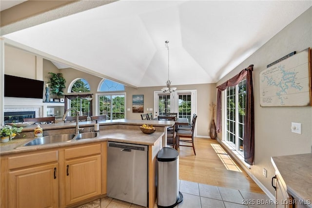 kitchen featuring sink, light tile patterned floors, light brown cabinetry, vaulted ceiling, and stainless steel dishwasher