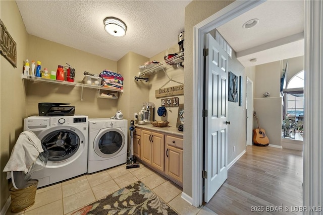 laundry area featuring light tile patterned flooring, separate washer and dryer, and a textured ceiling