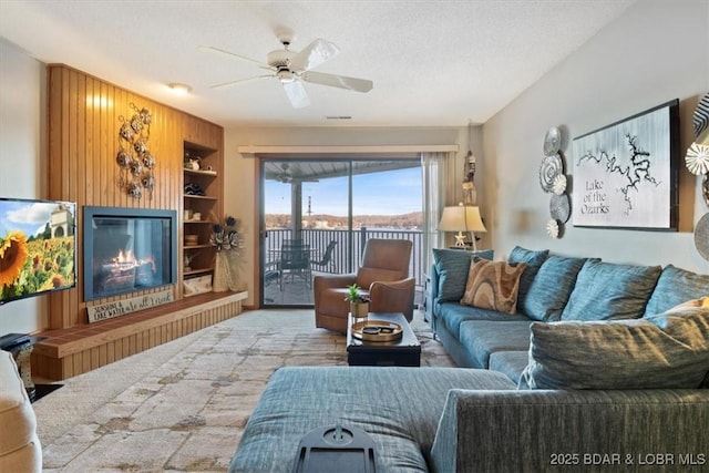 carpeted living room featuring ceiling fan, a textured ceiling, and built in shelves