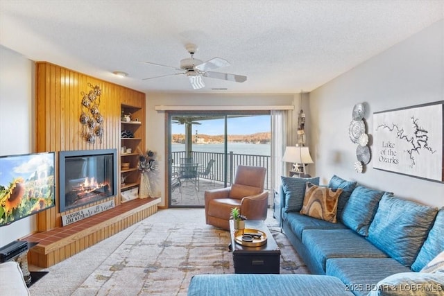 carpeted living room with a water view, ceiling fan, and a textured ceiling