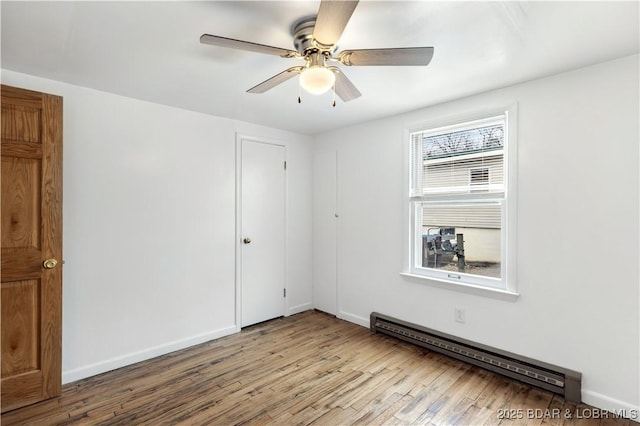 unfurnished room featuring a baseboard heating unit, light hardwood / wood-style floors, and ceiling fan