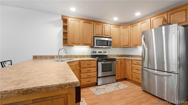 kitchen featuring sink, a breakfast bar area, appliances with stainless steel finishes, kitchen peninsula, and light wood-type flooring