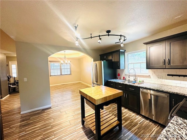 kitchen with wood-type flooring, appliances with stainless steel finishes, sink, and light stone counters