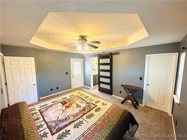 carpeted bedroom featuring ceiling fan, a barn door, a raised ceiling, and a textured ceiling