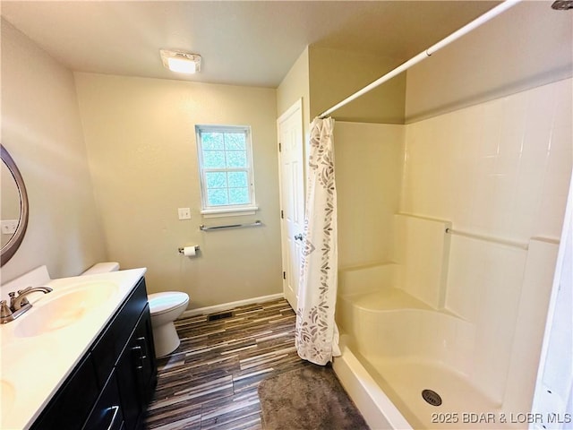 bathroom featuring hardwood / wood-style flooring, vanity, toilet, and walk in shower