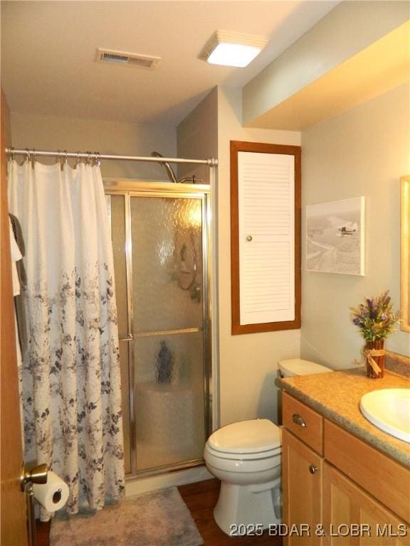 bathroom featuring toilet, vanity, a shower stall, and visible vents