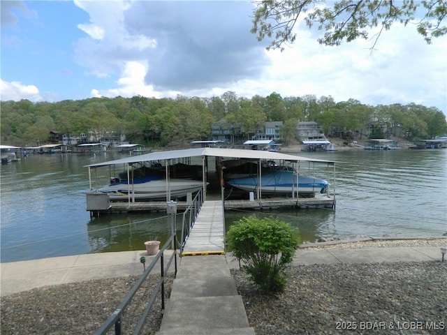 view of dock featuring boat lift, a wooded view, and a water view