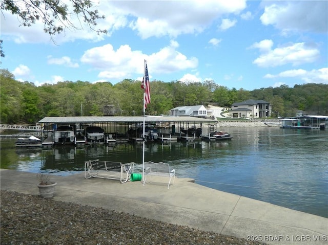 view of dock featuring a water view, a forest view, and boat lift
