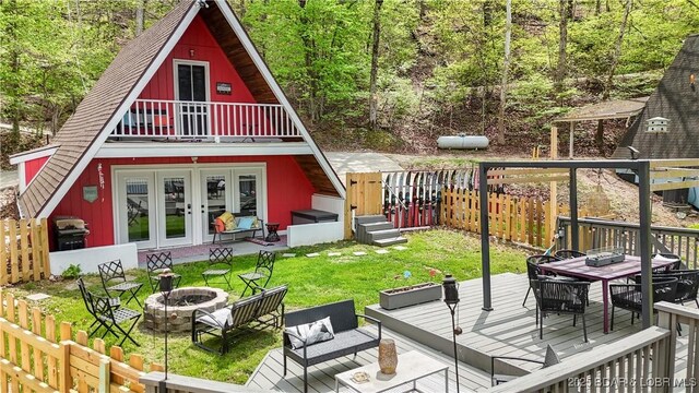 rear view of property featuring a yard, an outdoor living space with a fire pit, and french doors