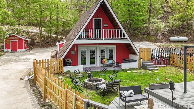 rear view of property featuring french doors, an outdoor fire pit, a yard, and a shed