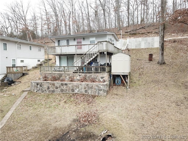 back of property featuring an outdoor structure, a shed, a wooden deck, and stairs