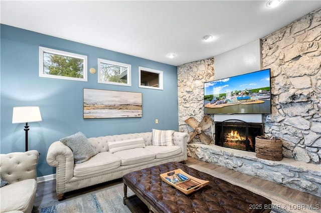 living room with a stone fireplace and wood-type flooring