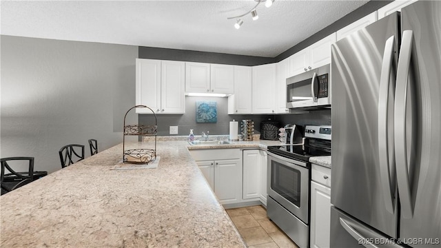 kitchen featuring white cabinetry, sink, stainless steel appliances, and a textured ceiling