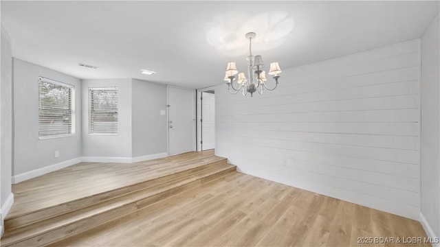 unfurnished dining area with a chandelier and light hardwood / wood-style flooring