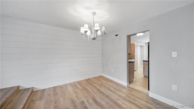 interior space with light hardwood / wood-style flooring, wooden walls, and a chandelier