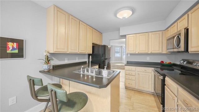 kitchen featuring sink, appliances with stainless steel finishes, a kitchen bar, light brown cabinetry, and kitchen peninsula